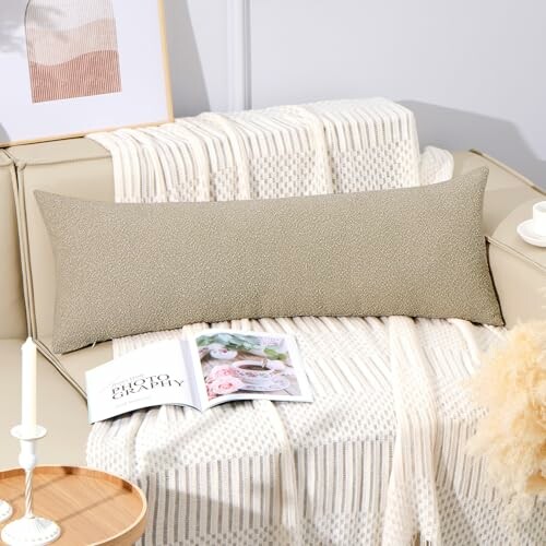 Beige decorative pillow on a sofa with a throw blanket and open magazine.