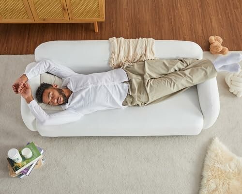 Man relaxing on a white sofa with books and coffee nearby