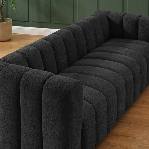 Black modern sofa with plush upholstery in a room with wooden flooring.