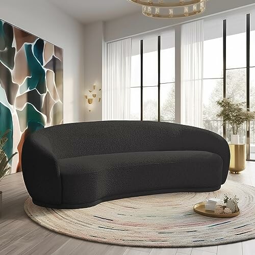 Stylish black sofa in modern living room with abstract art and large windows.