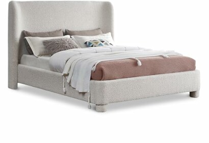 Modern upholstered bed with pillows and blankets.