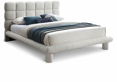 Modern upholstered bed with pillows and blanket.