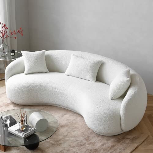 Modern white curved sofa with pillows in a living room.