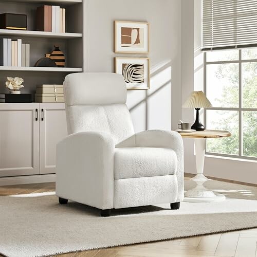 White recliner in a bright living room with bookshelf and window.