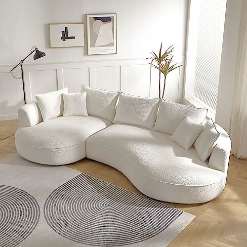 Curved white sectional sofa with pillows in a bright living room.