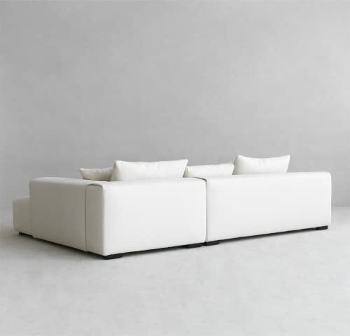 Back view of a modern white sofa with cushions against a plain background.