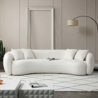 Modern white sofa in a minimalist living room with a floor lamp and geometric coffee tables.