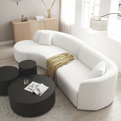 Modern white curved sofa with black round tables in a stylish living room