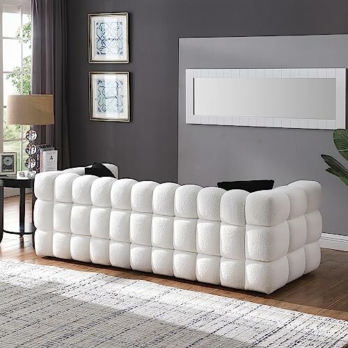 White tufted sofa in a modern living room with a large mirror and decor.