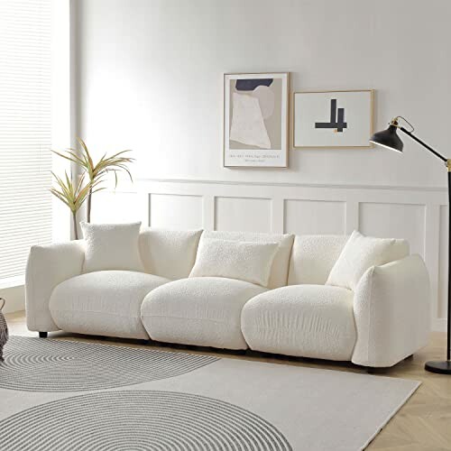 Modern white sofa in a stylish living room with abstract art and a floor lamp.