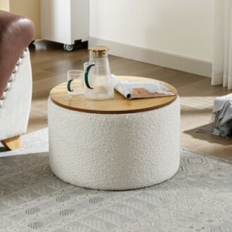 Round coffee table with a wooden top and white textured base, holding a glass pitcher, cups, and a magazine.